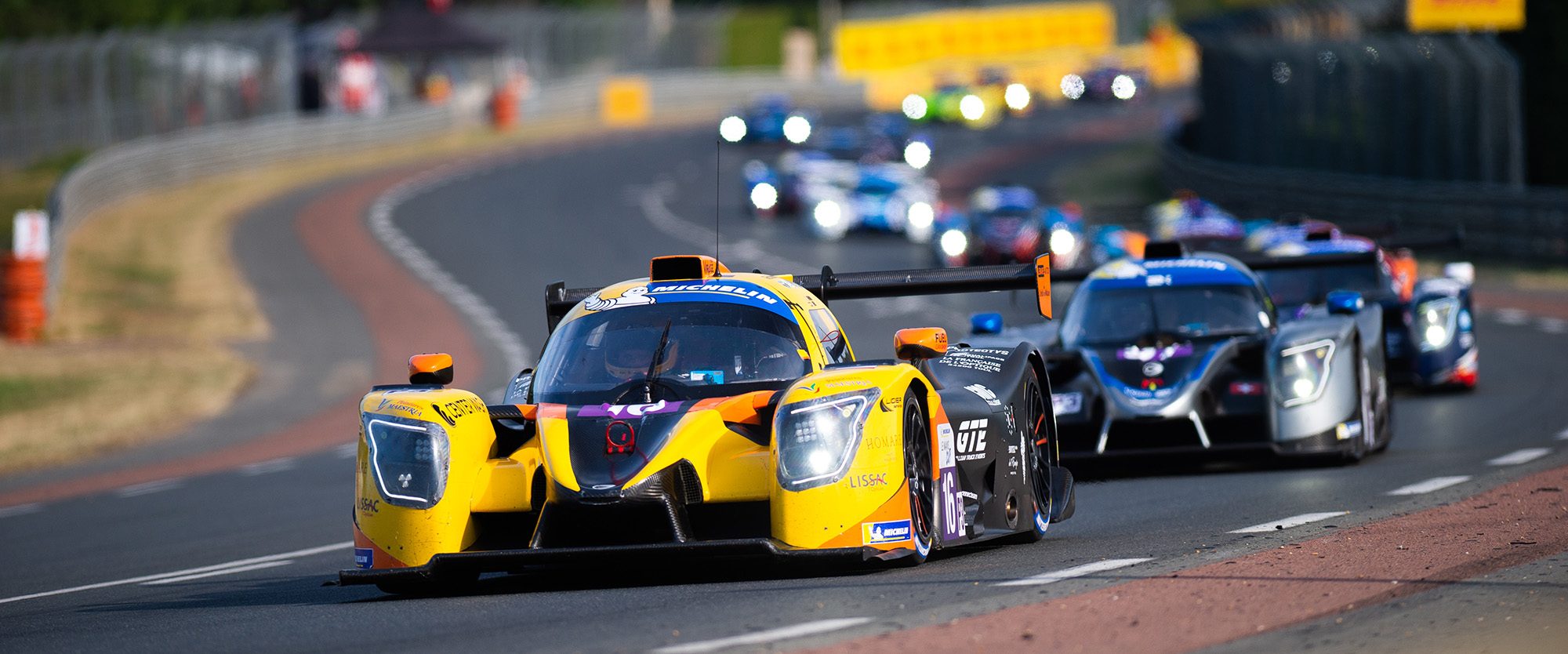 A yellow and black Team Virage Ligier LMP3 prototype leading a pack of cars at Le Mans